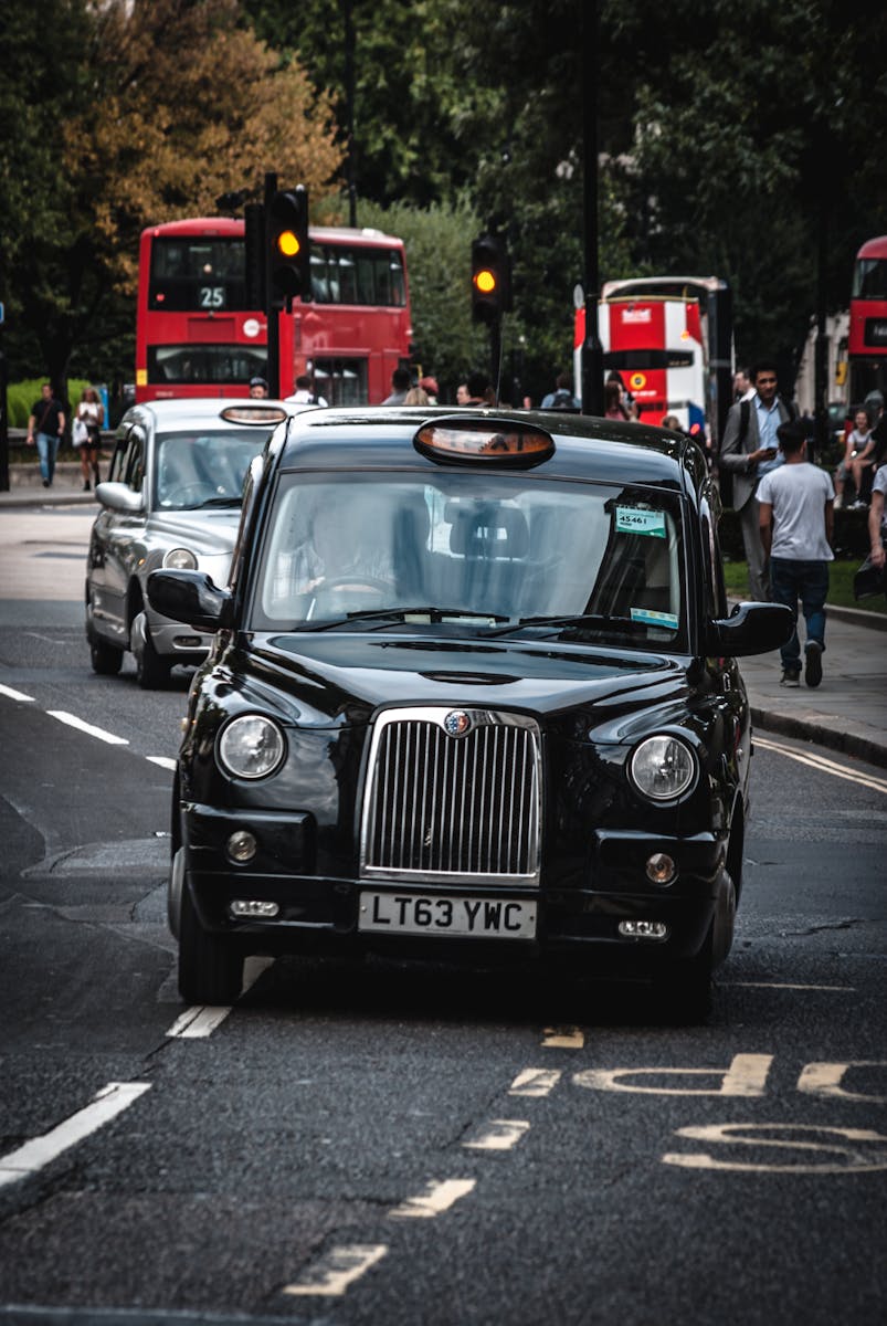 Classic black taxi navigating a bustling London street with red double-decker buses