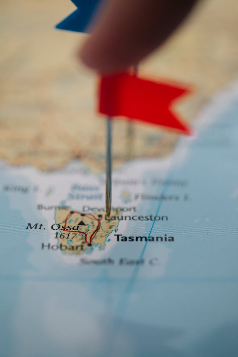 Close-up of a red flag marking Tasmania on a world map, highlighting travel destinations.