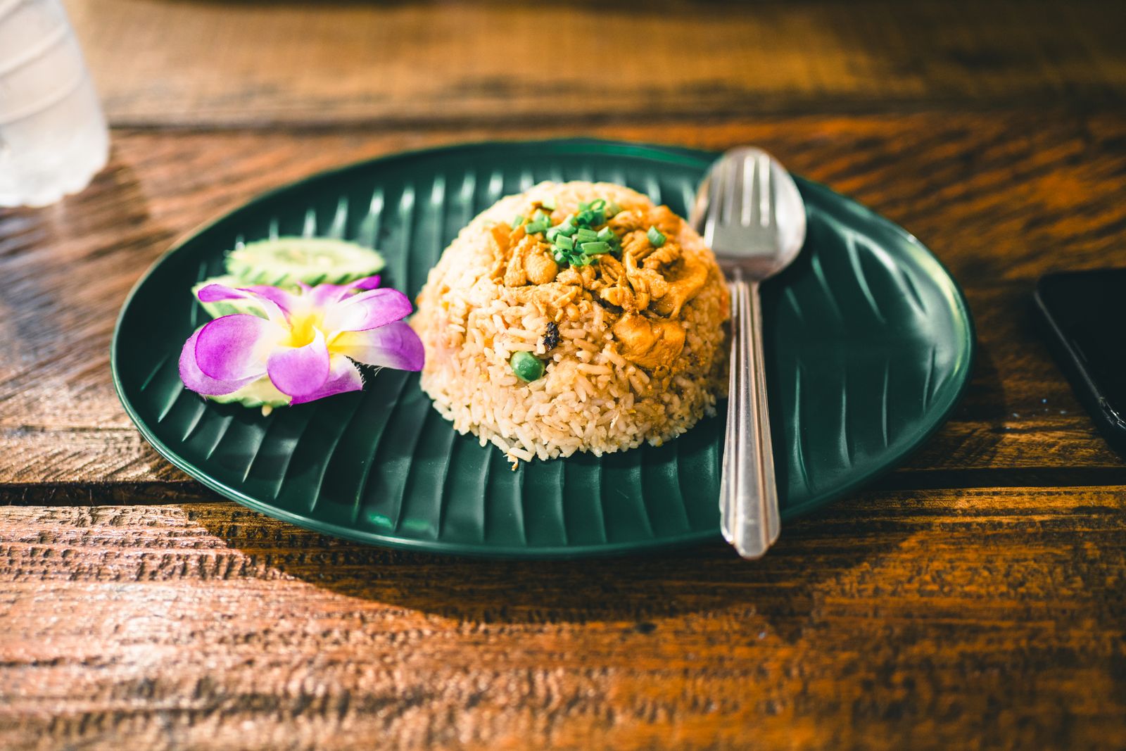 Delicious Thai fried rice served on a green plate, garnished with flower. Perfect for authentic Thai cuisine lovers.